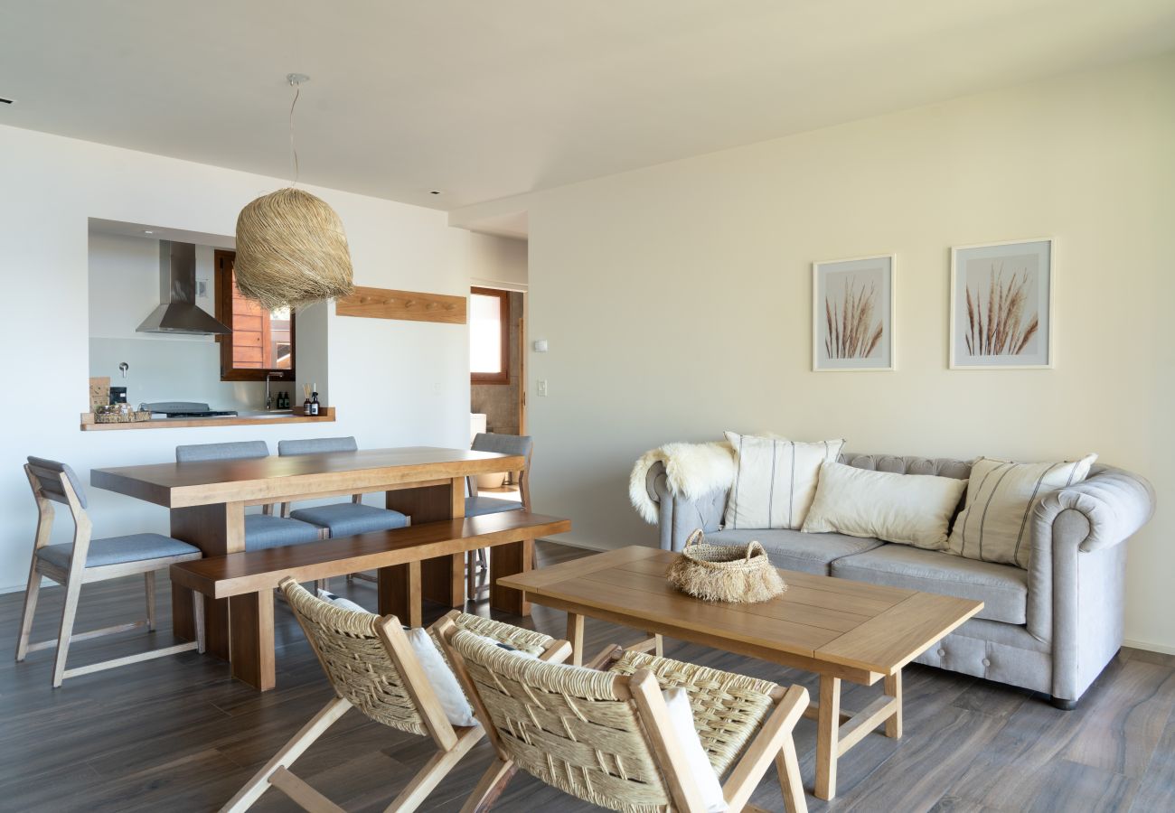 Living comedor del departamento Lenga 1D integrado con la cocina mediante una barra y distribución de concepto abierto.