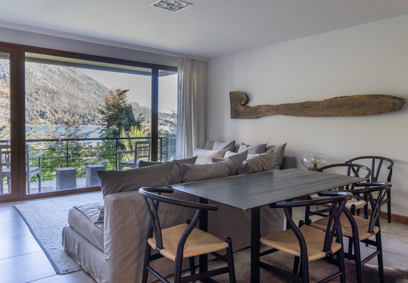 Living comedor del departamento Arrayán 1A con mesa de comedor, área de estar y vista panorámica al lago.